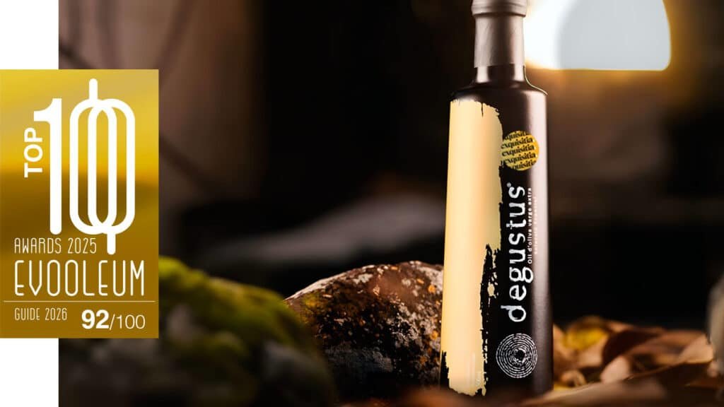 Aceite Degustus Selección Especial premiado con 92 puntos en EVOOLEUM, sobre fondo gourmet con iluminación cálida
